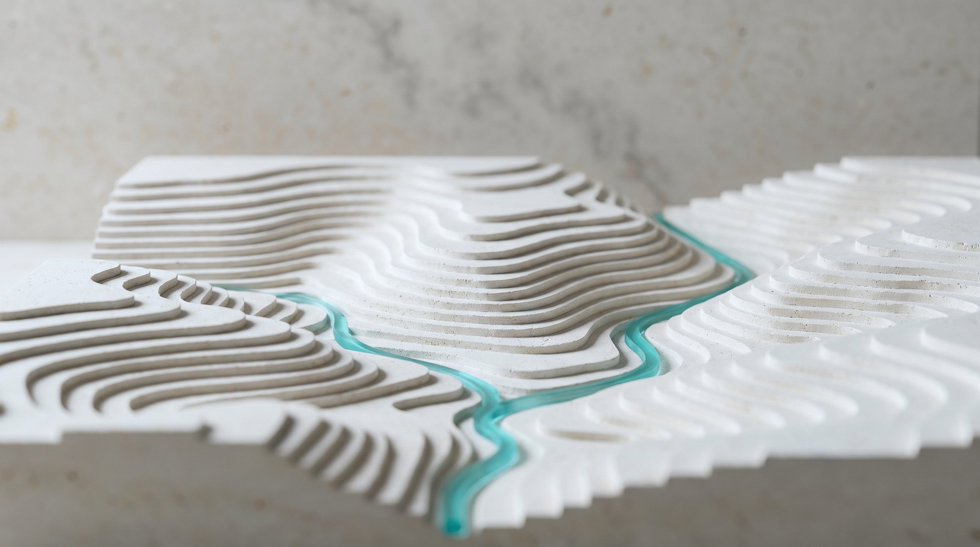 A sculpted limestone relief model of the Texas Hill Country with a ribbon of turquoise spring water
